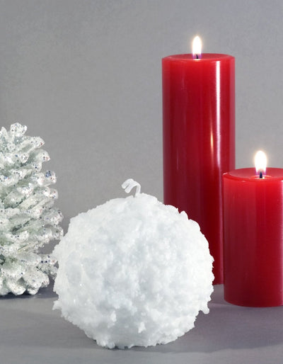 Snowball Candle 3" white with bumpy texture and two red pillar candles in background by Nordic Candle