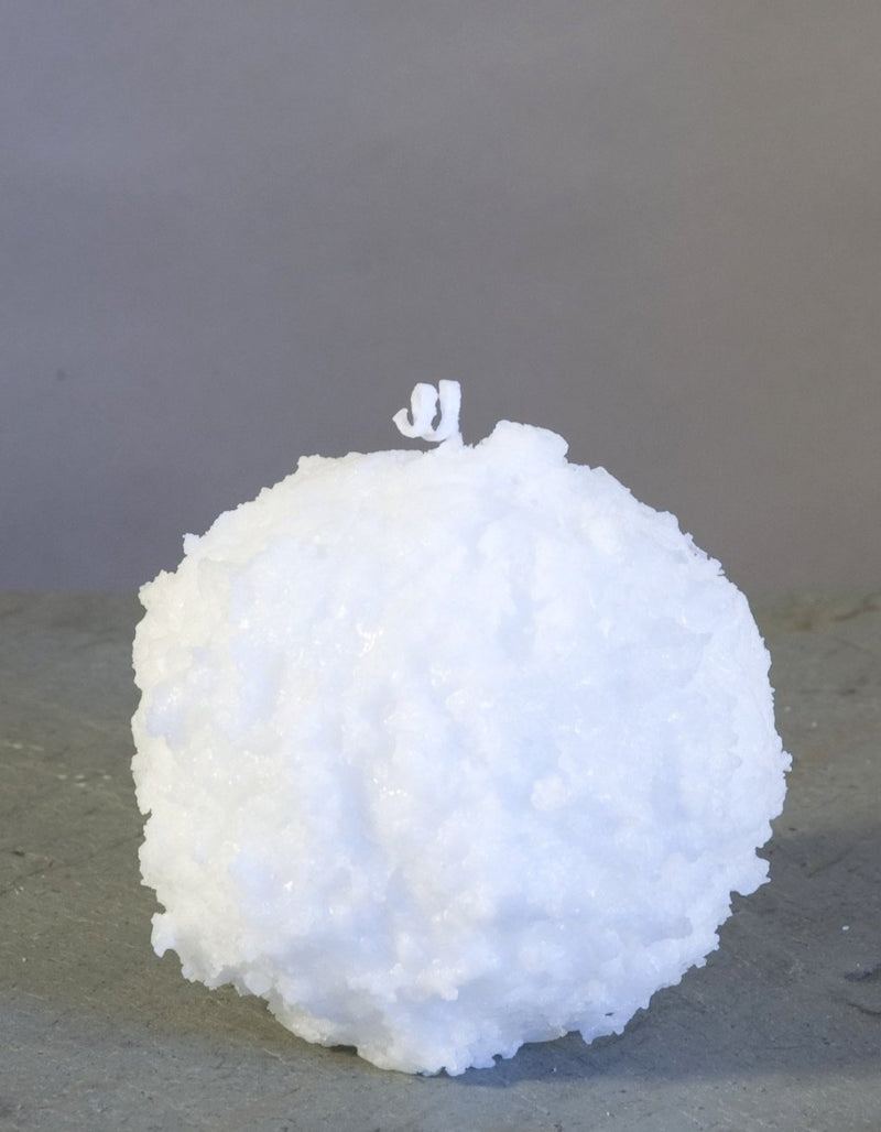 Snowball Candle 3" white with bumpy texture and two red pillar candles in background by Nordic Candle